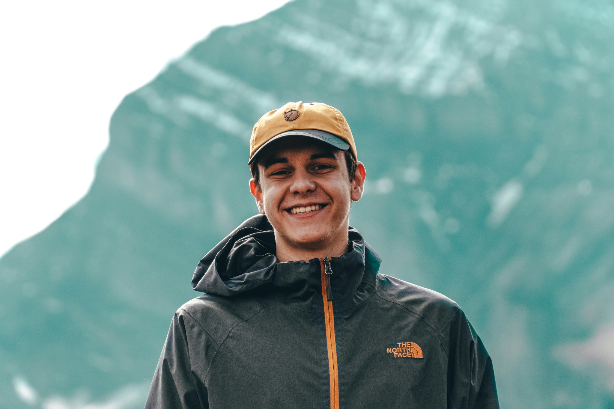 Ben wearing a yellow cap, outdoors with mountains in the background